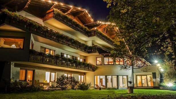 A multi-story hotel with balconies, outdoor seating, and a well-lit entrance.