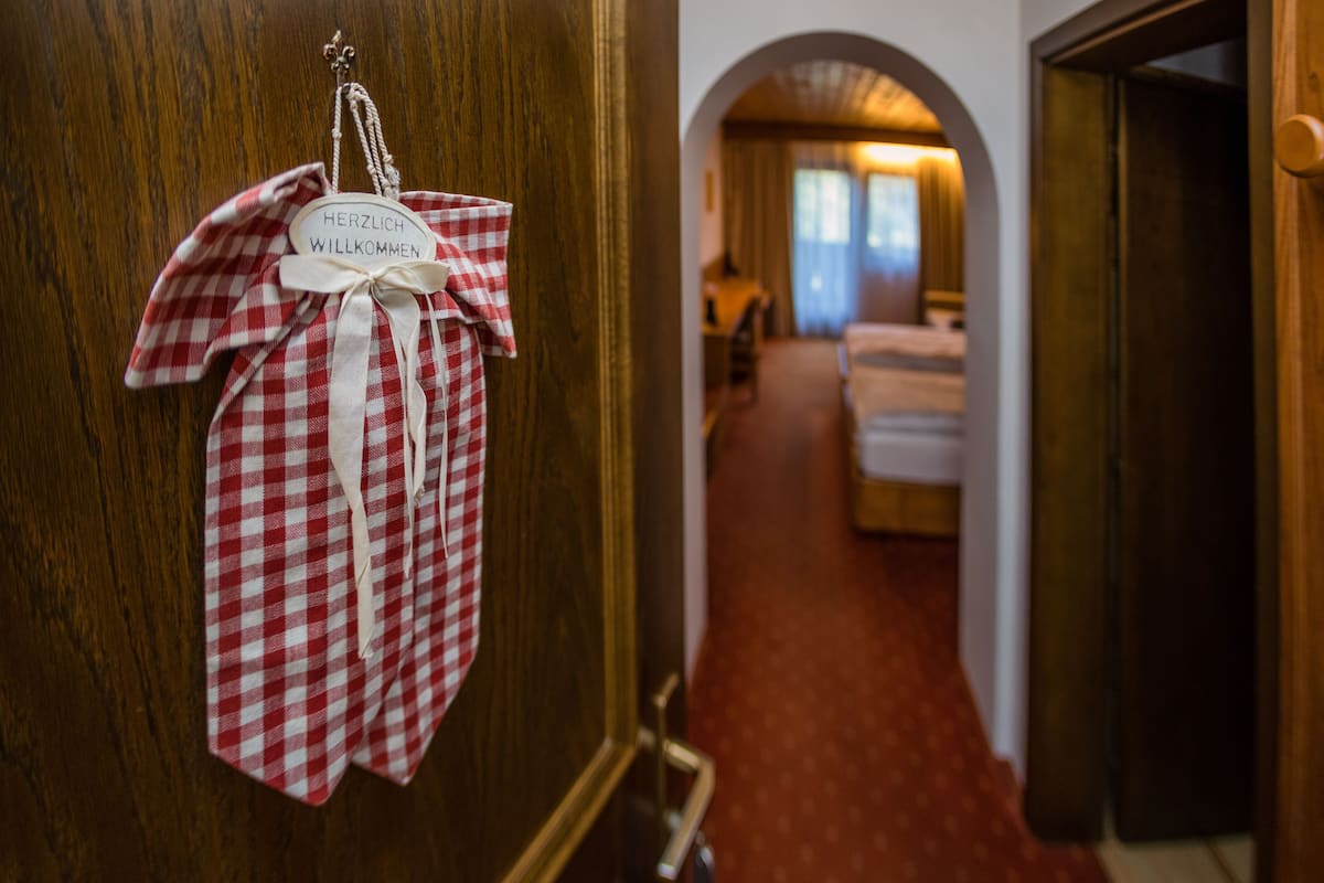 A red and white checkered cloth hanging on a wooden door with a sign that reads "Herzlich Willkommen."