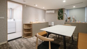 Una cocina moderna con horno integrado, un lavamanos y una encimera. Hay una zona de comedor con una mesa y sillas.