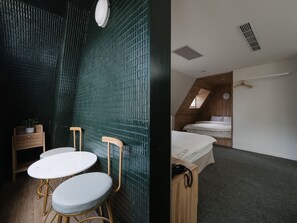 A compact room with a sloped ceiling, a bed, a small table, and a chair.