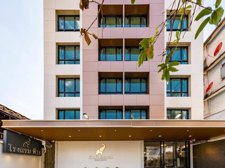 Un immeuble d’hôtel à plusieurs étages, doté d’une façade moderne, d’un hall d’entrée couvert et d’une enseigne indiquant qu’il s’agit de l’hôtel P18 à Bangkok.