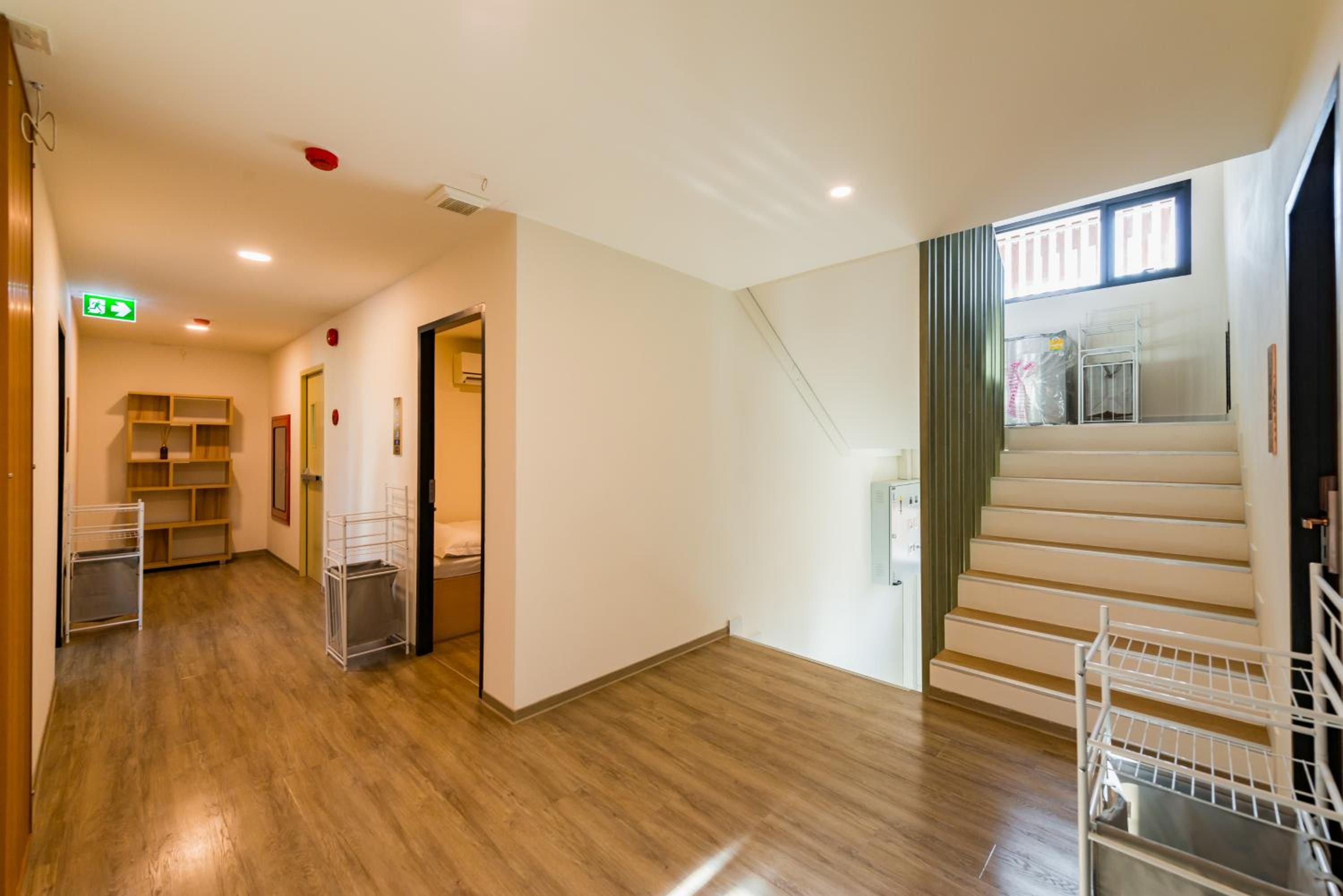 A hotel hallway with wooden flooring, a staircase, and a view of a balcony.