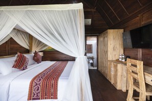 Ein Zimmer mit einem Bett unter einem Baldachin, Holzmöbel und einem Fernseher.
