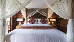A large bed with white linens, a wooden headboard, and two bedside lamps.
