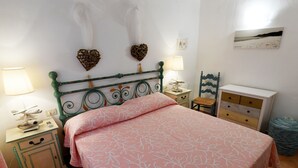 A bedroom with a bed, two nightstands, a dresser, a lamp, and decorative items on the wall. - Belvedere (Arzachena)