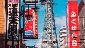 A busy urban street with neon signs and a prominent tower in the background.