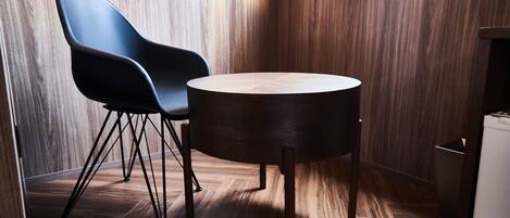 Rincón de una habitación con una mesa redonda de madera y una silla negra moderna.