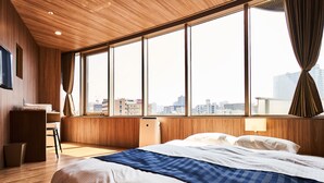 Une chambre d’hôtel dotée d’une grande fenêtre, d’un plafond en bois et d’un lit avec une literie blanche et bleue.