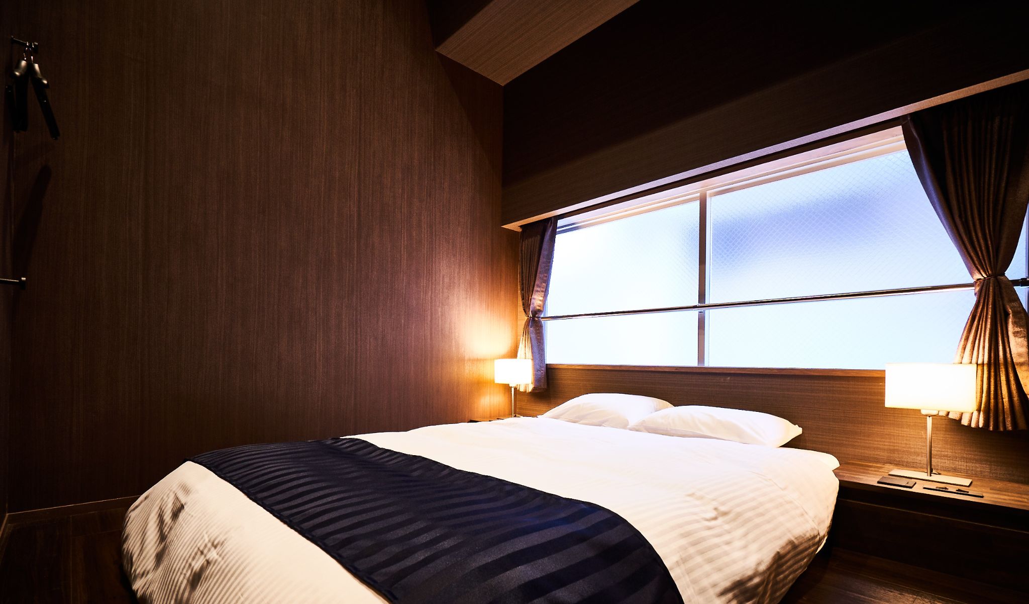 Een hotelkamer met een bed, nachtkastjes en een raam.