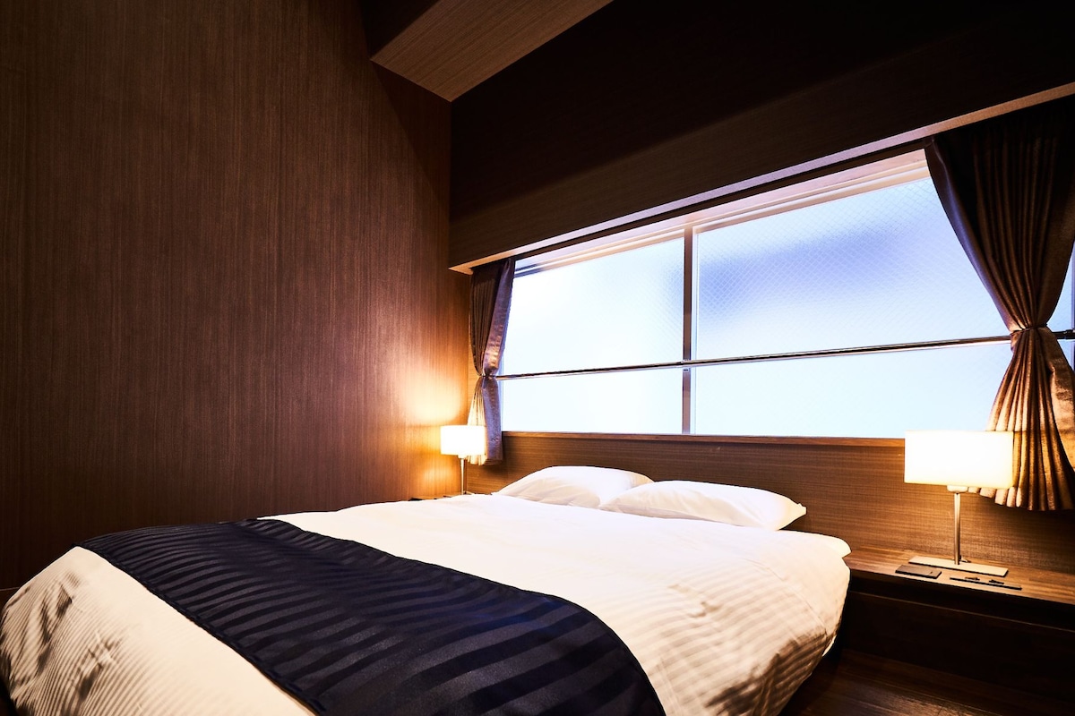A hotel room with a bed, nightstands, and a window.