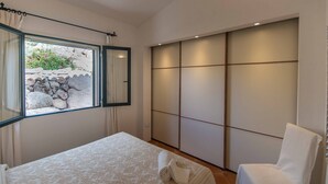 Une chambre à coucher avec un lit, une chaise, une fenêtre avec des rideaux et une porte coulissante.