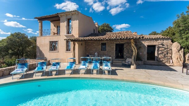 A two-story stone building with a swimming pool and lounge chairs. - Villa Noelia (Arzachena)