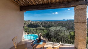 A balcony with a view of a mountainous landscape and a swimming pool. - Villa Noelia (Arzachena)