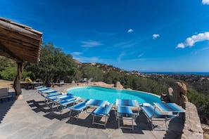 A pool area with lounge chairs and a view of the landscape.