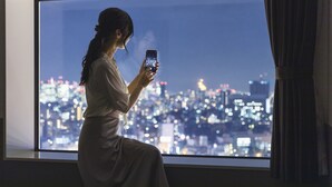 A person sitting by a window with a cityscape view. - Hotel Crown Hills Ueno Premier (Tokyo)