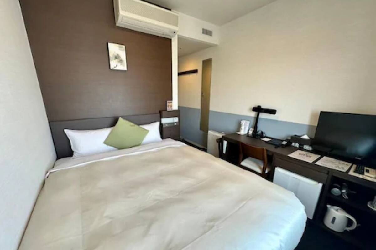 Een hotelkamer met een bed, bureau, stoel, televisie en koffiezetapparaat.