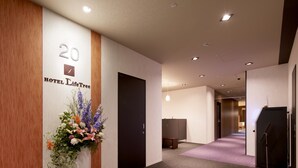 A modern hotel lobby with a reception desk, a large floral arrangement, and a sign indicating room number 20. - Hotel Crown Hills Ueno Premier (Tokyo)