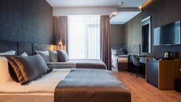 Une chambre d’hôtel moderne équipée de deux lits, d’un bureau, d’une chaise, d’une télévision et d’une grande fenêtre avec des rideaux.