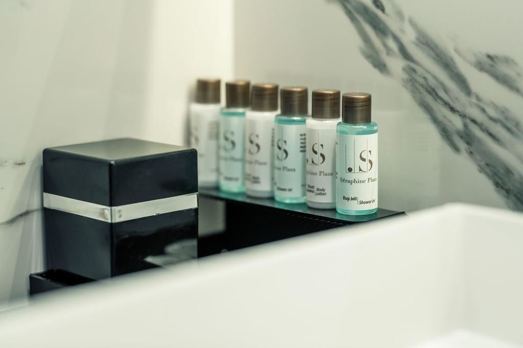 A row of bottles labeled 'Sérine Plan' on a black shelf in a bathroom.