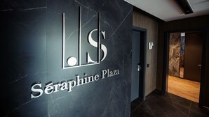 Un interior moderno con una pared de mármol que muestra el logotipo y el nombre 'Seraphine Plaza'.