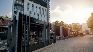 Un edificio moderno con una cafetería en la planta baja, mesas al aire libre y un letrero que dice "Séraphine Plaza".
