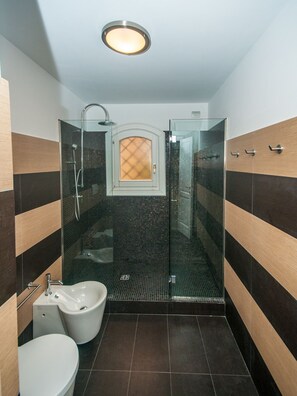 A modern bathroom with a glass-enclosed shower, a white sink, and a toilet. - Oleandri 101 (Arzachena)