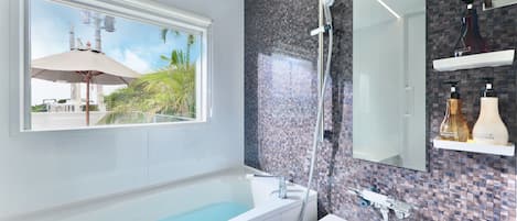 A modern bathroom with a large bathtub, a shower, and a window with an umbrella.