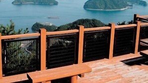 Una terraza de madera con barandilla, que da vista a un cuerpo de agua con varias islas.