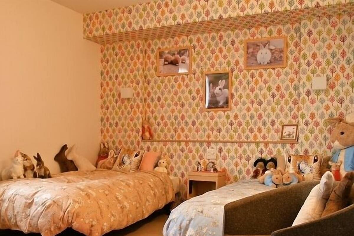 A room with two beds, a chair, a rug, and wall decorations.