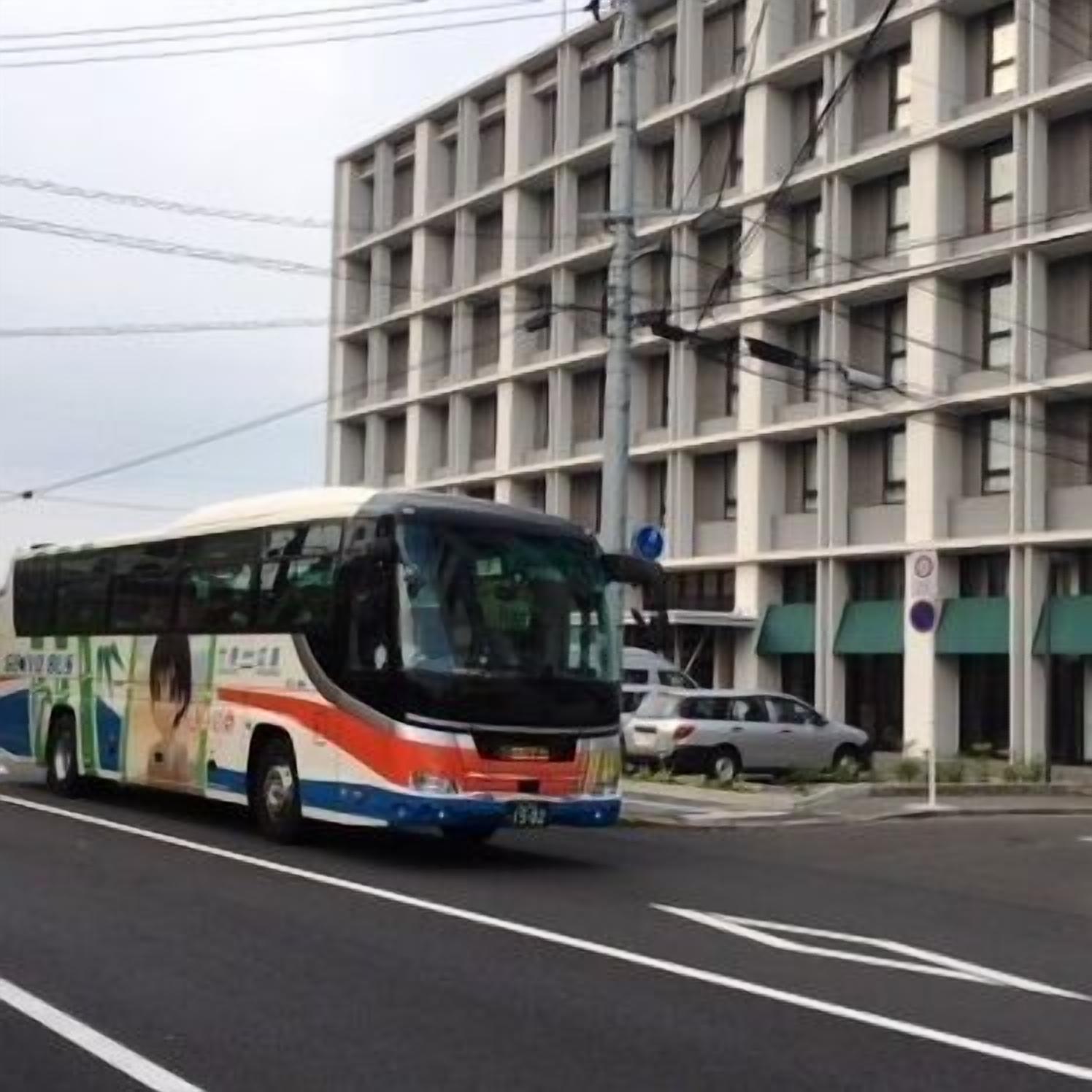 Un autobus sur une route, avec un immeuble à plusieurs étages en arrière-plan.
