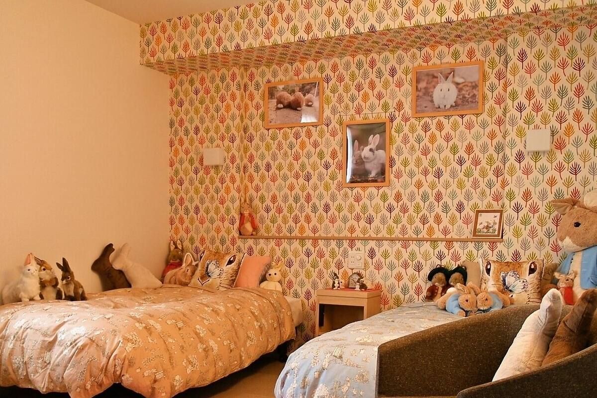 A bedroom with two beds, a chair, a rug, and wall decorations including framed pictures.