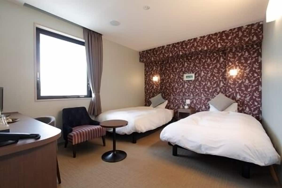 Una habitación de hotel con dos camas, un escritorio, una silla y una mesita redonda.