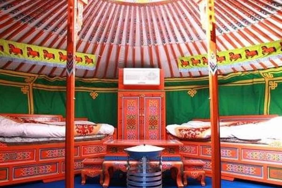 A traditional room with four beds, a central table, and a decorative ceiling.