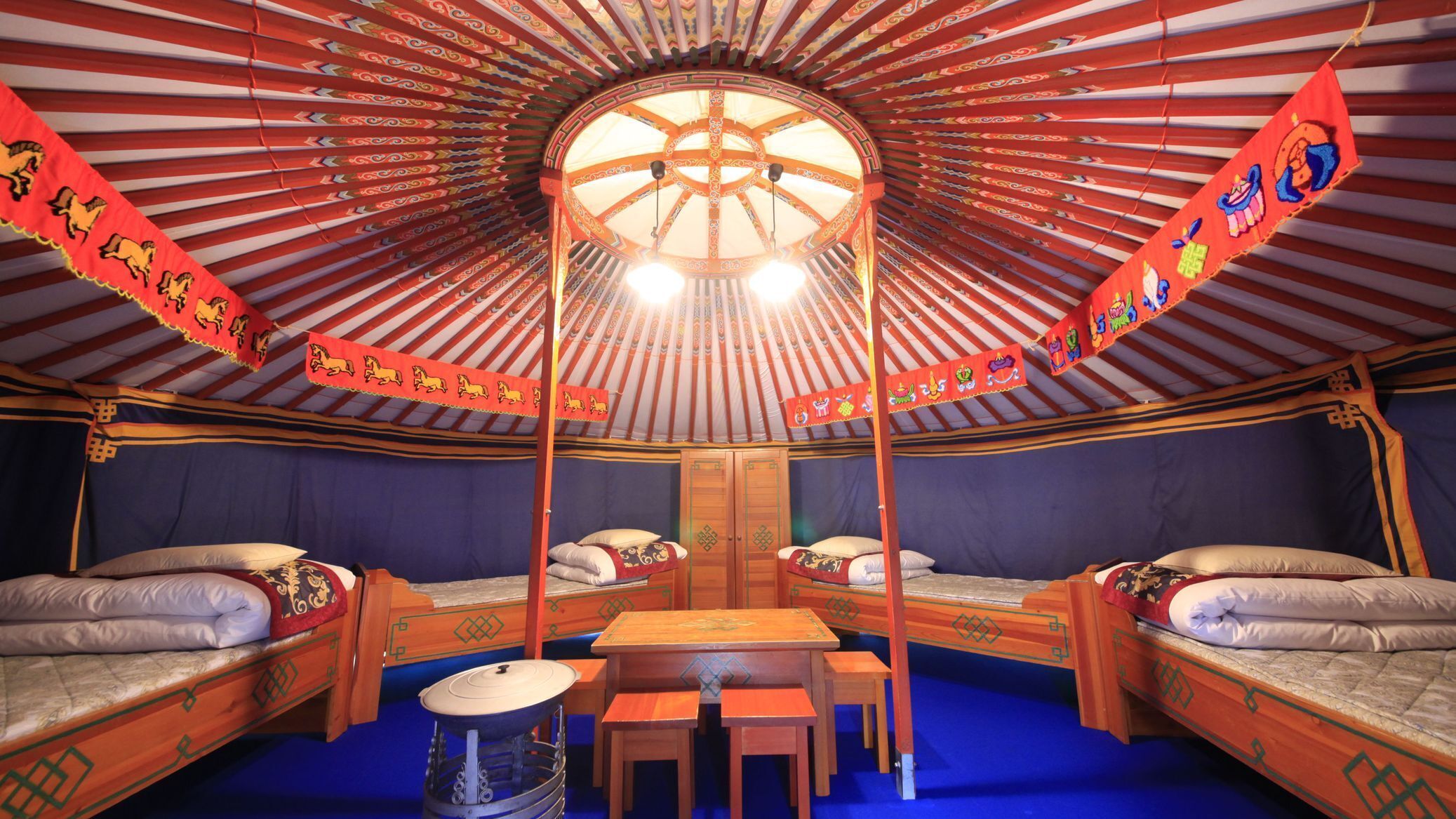 A traditional yurt with two beds, a central table, and a drum.