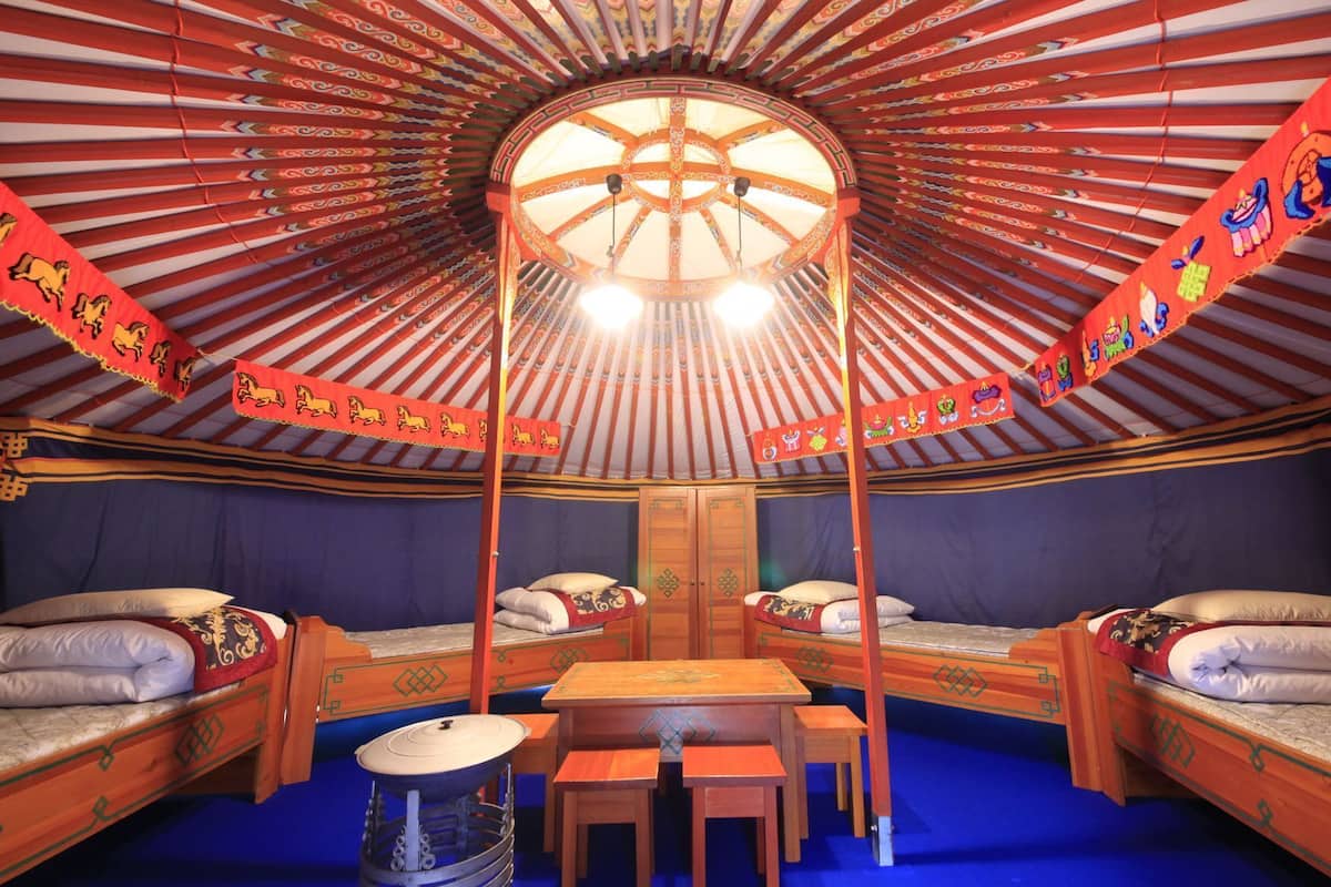 A traditional yurt with two beds, a central table, and a drum.