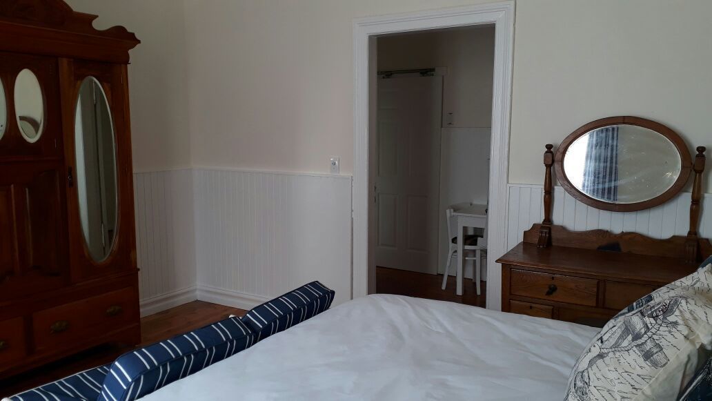 A bedroom with a bed, a dresser, a mirror, and a door leading to a bathroom.