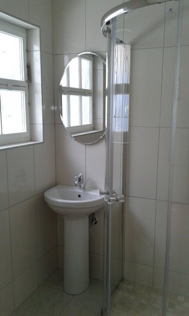 Ein Badezimmer mit einem Standwaschbecken, einem Spiegel und einer Duschkabine aus Glas.