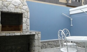 A stone fireplace with a blue wall and a white metal table with chairs. - Jetty Self-Catering Swakopmund (Swakopmund)