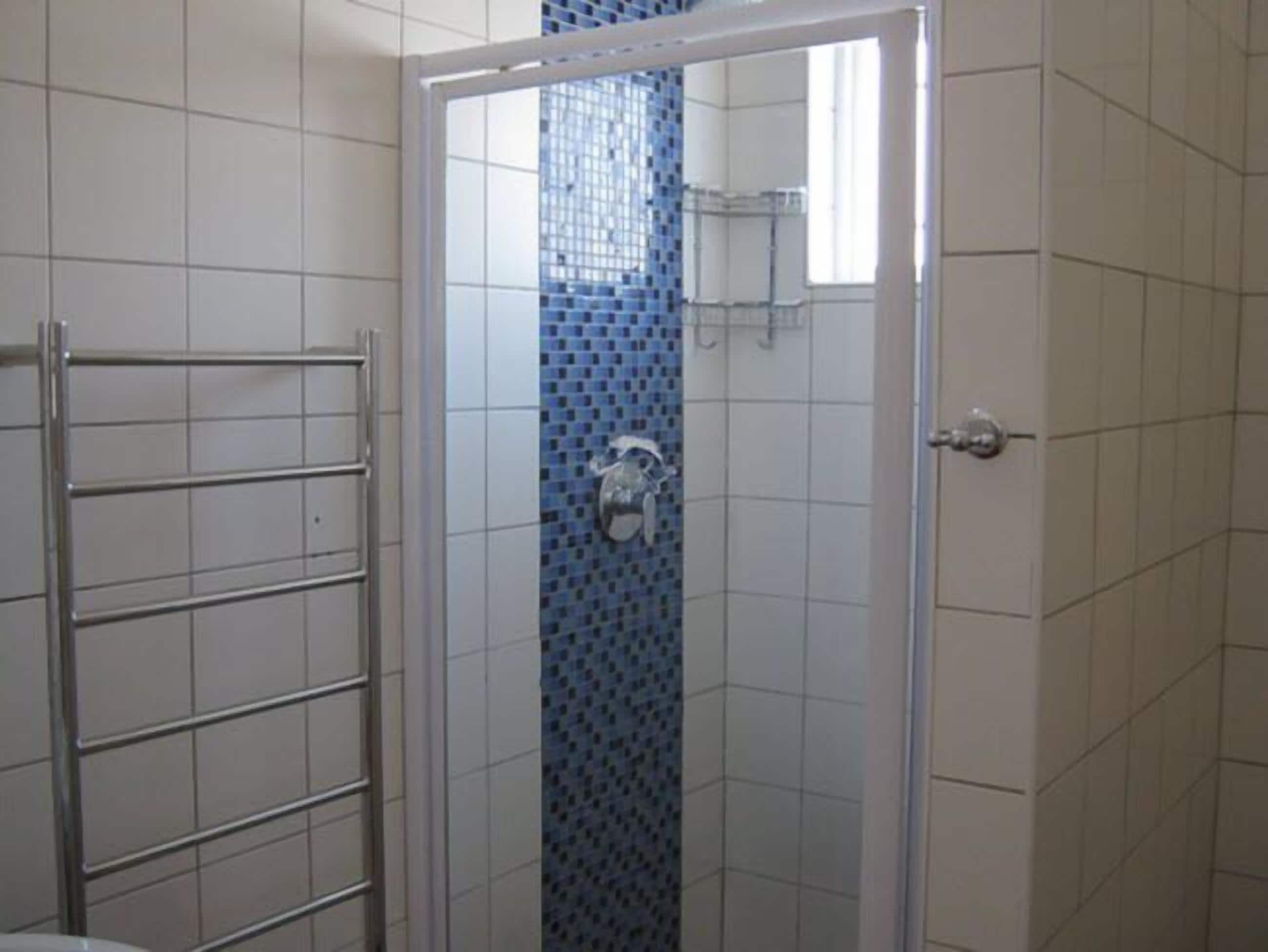 Ein Badezimmer mit Duschkabine, Handtuchhalter und Toilette.