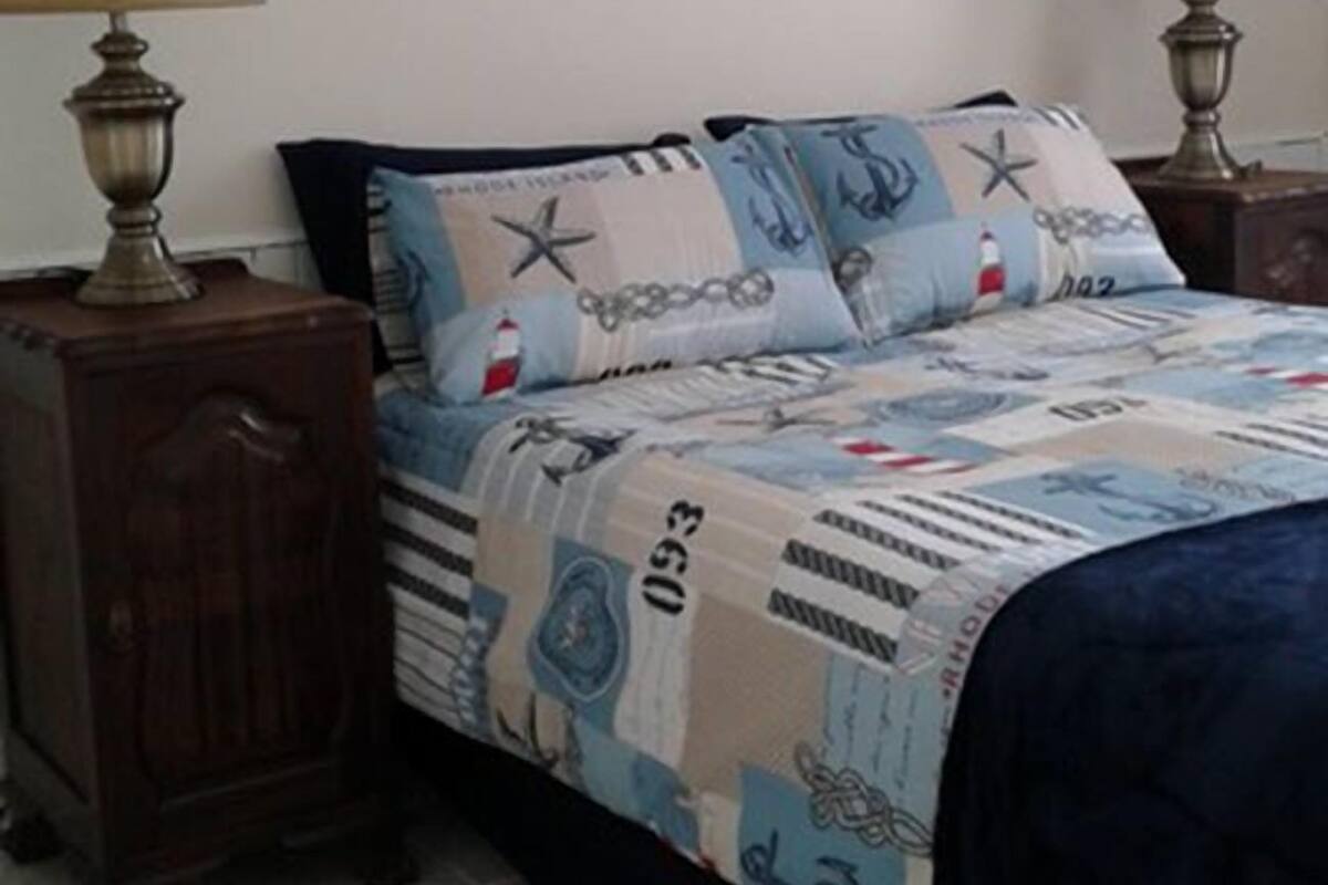 A bedroom with a bed, two nightstands, and a wall-mounted life preserver.