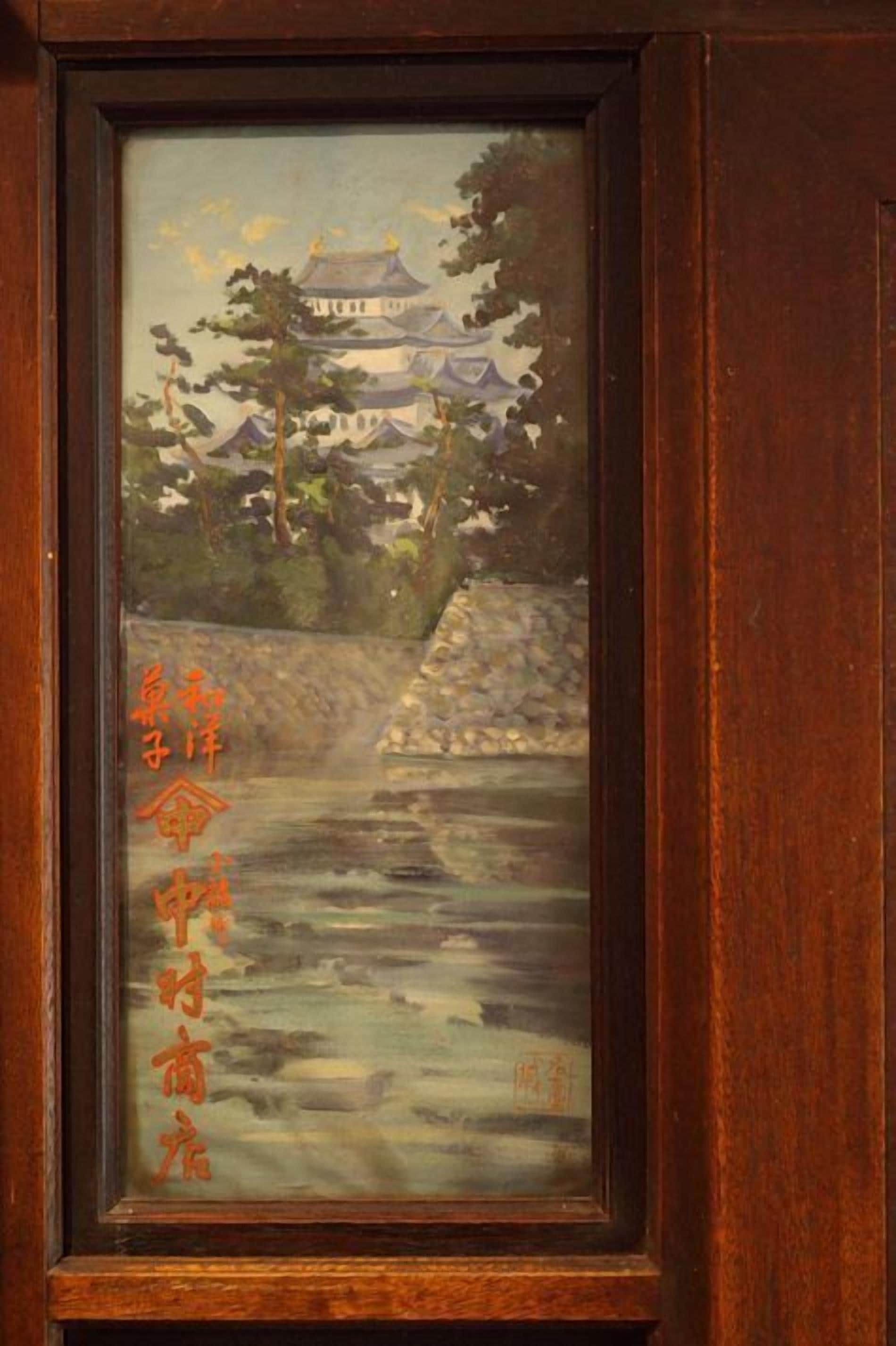 A framed painting of a traditional Chinese pagoda by a river, with Chinese calligraphy on the left side.