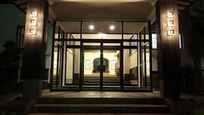 A building entrance with a covered porch, glass doors, and steps leading up to the entrance. - Yakushikan (Komoro)