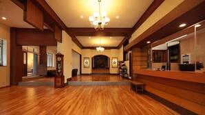 A spacious lobby with wooden flooring, a grand chandelier, and a reception desk. - Yakushikan (Komoro)