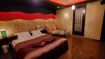 A modern hotel room with a large bed, a seating area, and a door.