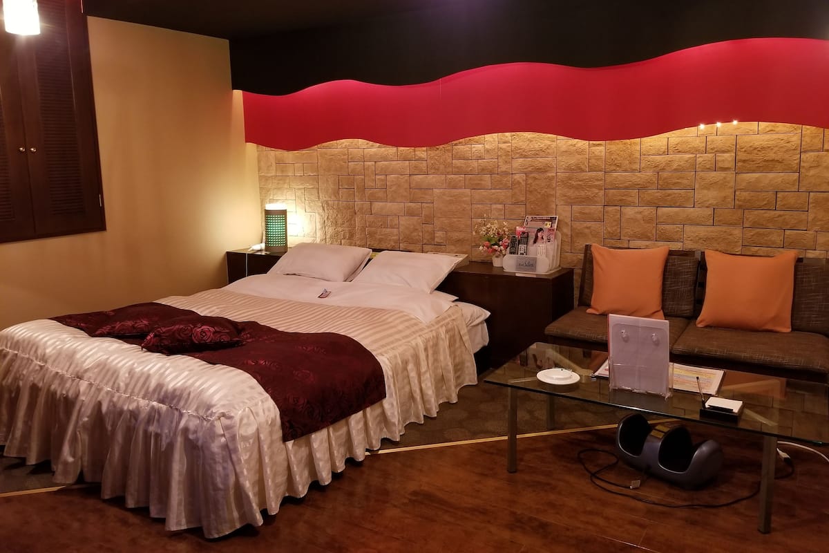Ein Hotelzimmer mit Bett, einer Couch, einem Glastisch und einer Wand mit Steinoptik.