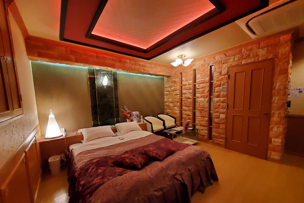 Ein Schlafzimmer mit einem großen Bett, einem Nachttisch, einem Sessel, einem Schreibtisch und einem Kleiderschrank.
