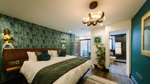 A modern bedroom with a large bed, a patterned wall, and a view of the bathroom. - Absoluxe Suites (Carnforth)