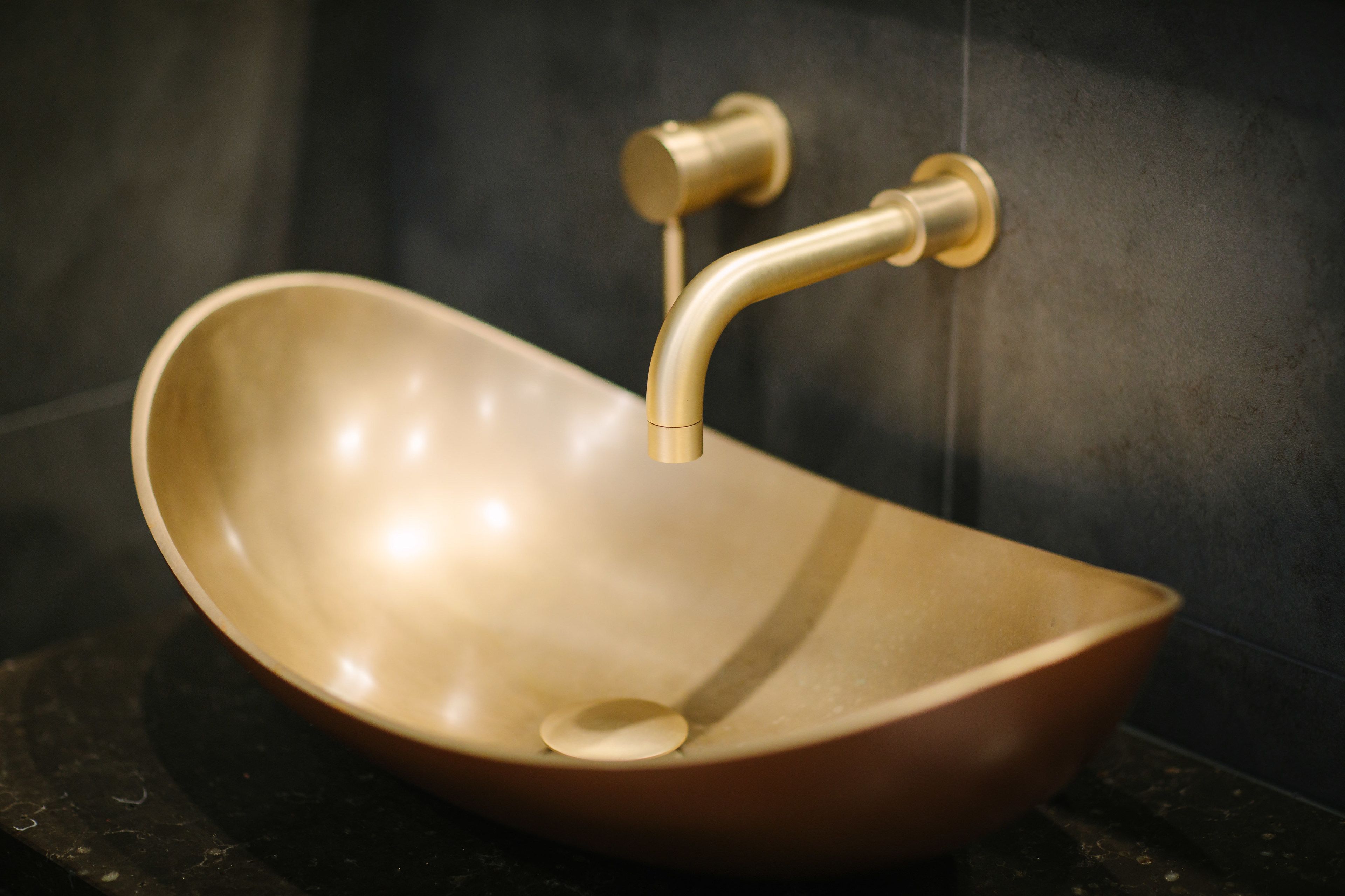 A modern bathroom with a unique bowl-shaped sink and a curved faucet.
