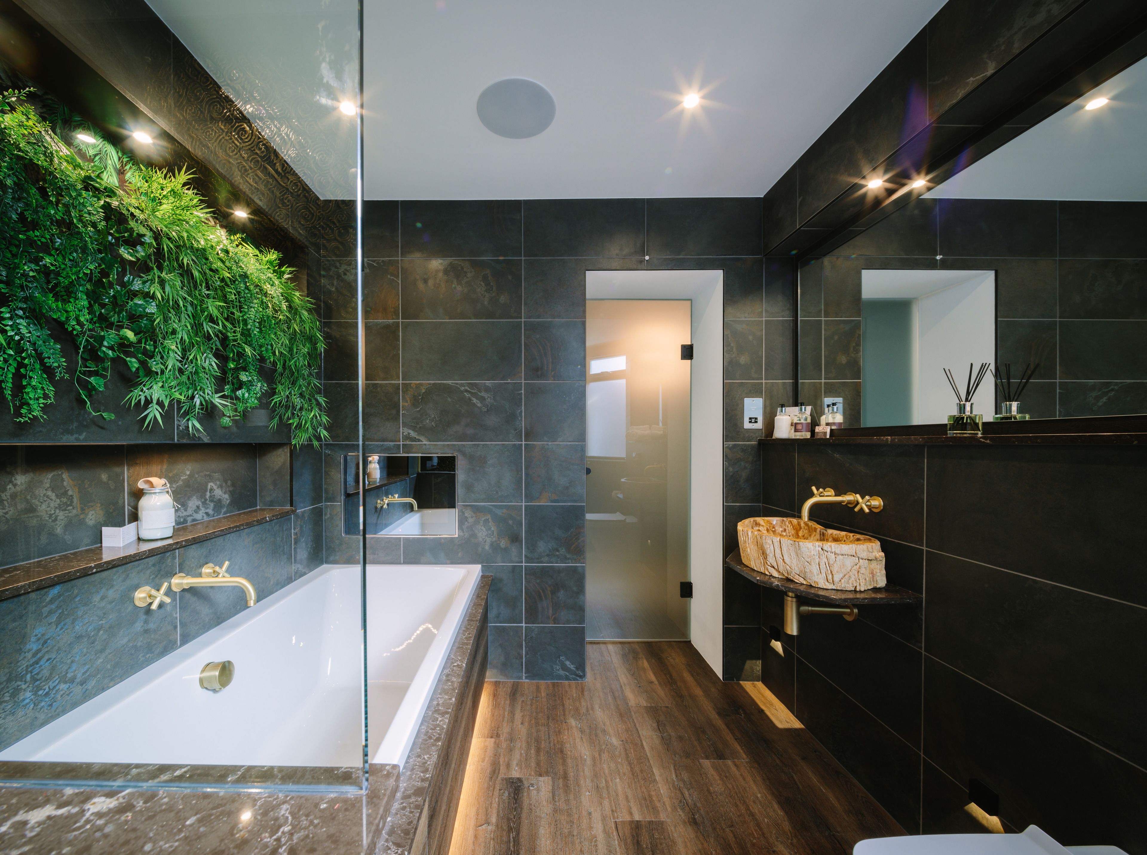 Une salle de bain moderne avec une grande baignoire, un meuble-lavabo en bois et un mur végétal.