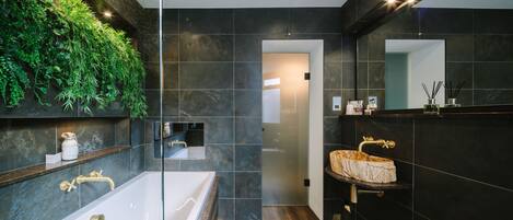 Une salle de bain moderne avec une grande baignoire, un meuble-lavabo en bois et un mur végétal.